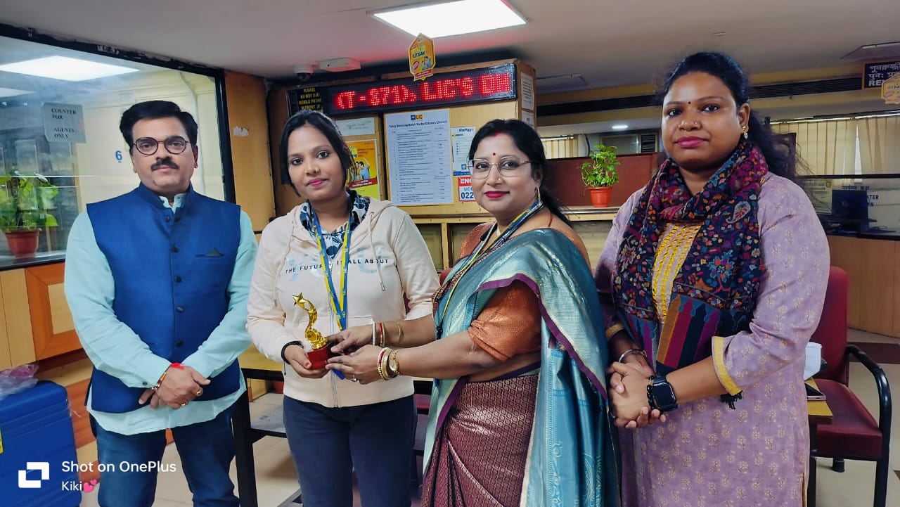 man wearing a black jacket, white shirt, blue jeans, and brown boots, playing a white electric guitar while sitting on an amp
